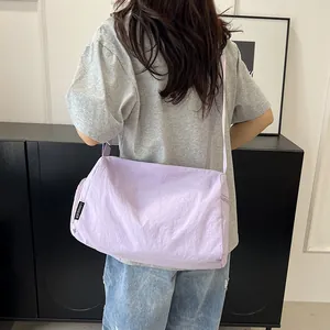 Détail du sac bandoulière en nylon violet clair avec sangle réglable et étiquette logo