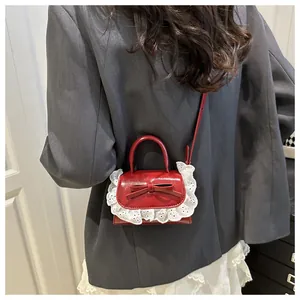 Détail d'un mini sac à main rouge avec nœud et dentelle blanche porté par un modèle
