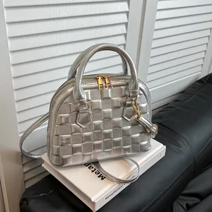 Detail of silver shell bag with checkered embossing and shiny metallic golden hardware