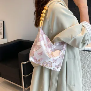 Sac hobo rose brodé de papillons avec bandoulière ornée de perles de bois naturelles