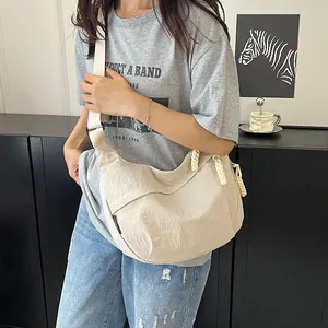 Dettaglio della borsa a tracolla in nylon beige con zip intrecciata e spallina larga