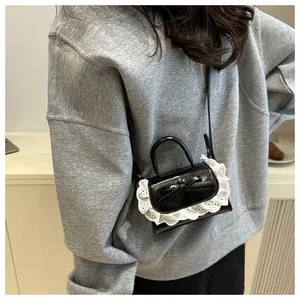 Vue détaillée du mini sac noir brillant avec bordure en dentelle blanche et nœud élégant