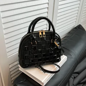 Detail of black patent shell bag featuring woven checkerboard texture and gold hardware