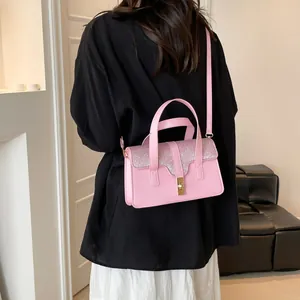 Sac à main élégant rose à motif crocodile porté en bandoulière sur tenue noire