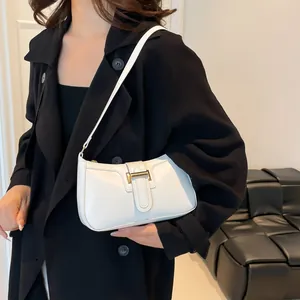 Minimalist white crescent shoulder bag with gold buckle accessory on black trench coat