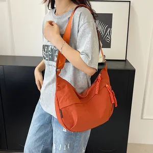 Dettaglio della borsa a mezzaluna in nylon arancione con tracolla larga e cursore testurizzato