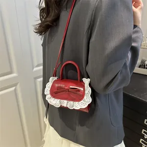 Mini sac rouge avec nœud et bordure en dentelle blanche porté par un mannequin