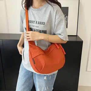 Vista ravvicinata della borsa a mezzaluna in nylon arancione con tracolla e cerniera robusta