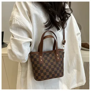 Detailed view of a brown checkered tote bag with gold rivet accents on the handle