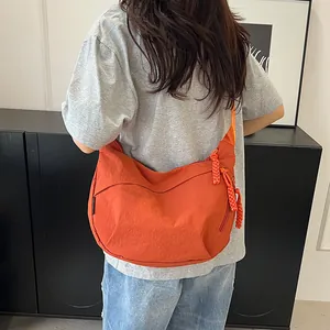 Dettaglio di una borsa a mezzaluna arancione con zip intrecciata ed etichetta laterale