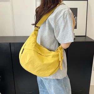 Dettaglio di una borsa a mezzaluna in nylon giallo vivace con ciondolo intrecciato
