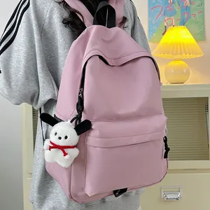 Pink nylon backpack with cute puppy charm shown from a side-view on a female model
