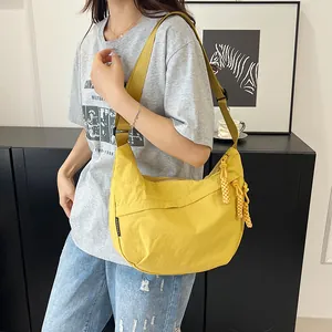 Dettaglio della borsa dumpling gialla in nylon con tracolla larga e tirazip a nodo intrecciato