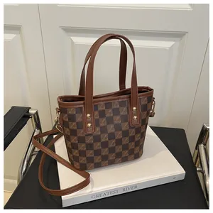 Close-up of brown checkered bucket bag with leather handles and metallic hardware