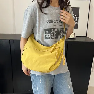 Dettaglio della borsa a mezzaluna in nylon giallo con tripla zip e tiranti intrecciati