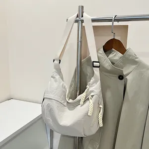 Dettaglio borsa a mezzaluna in nylon beige stropicciato con tasche e tirazip intrecciati