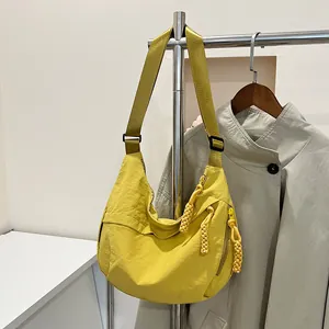 Dettaglio macro della borsa a mezzaluna in nylon giallo con tirante in corda e tracolla