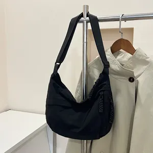 Dettaglio della borsa a tracolla nera a mezzaluna con tirante della zip intrecciato
