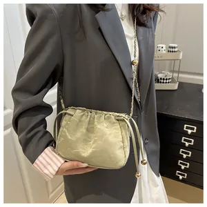 Detail of light green drawstring bucket bag with gold chain and decorative metal ball