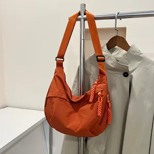 Dettaglio della borsa a mezzaluna in nylon arancione con tiretti della zip intrecciati