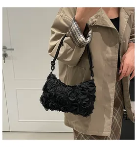 Detail view of a black ruffled lace shoulder bag with elegant 3D textile rose flowers