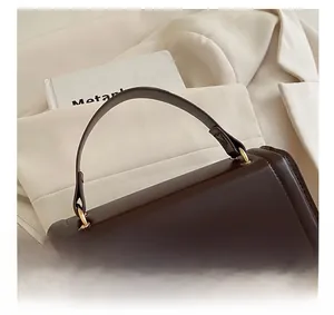 Detaillierte Nahaufnahme einer dunkelbraunen Handtasche mit goldener Metallschließe