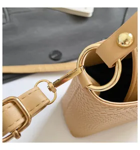 Close-up of beige woven bucket bag with glossy gold hardware and detailed stitching