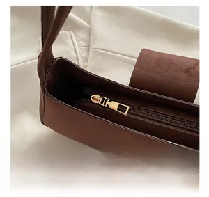 Dettaglio della borsa in pelle scamosciata marrone con cerniera dorata e chiusura magnetica