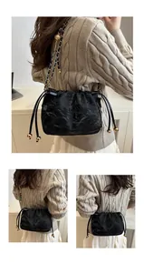 Detail of black drawstring bag with pleated texture and golden metal ball chain strap