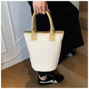 Close-up of V-shaped weaving pattern on cream-colored straw bucket bag with brown handles