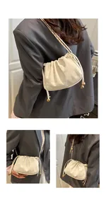 Detailed view of a cream white drawstring bucket bag with a thin gold chain strap