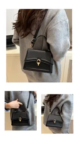 Detail der schwarzen Ledertasche mit rundem goldfarbenem Verschluss und fester Klappe
