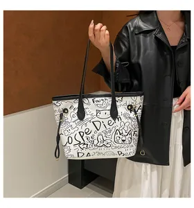 Dettaglio della borsa tote in tela con graffiti neri e fibbie metalliche decorative