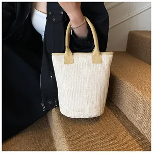 Close-up of woven straw bucket bag featuring yellow handles and herringbone texture