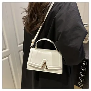 Details einer weißen Ledertasche mit goldener V-Schnalle und elegantem Tragegriff
