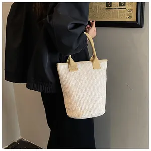 Detailed herringbone weave texture on a cream straw bucket bag with soft fabric handles