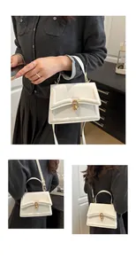 Nahaufnahme einer weißen Klapphandtasche mit goldenen Ringen und abnehmbarem Gurt