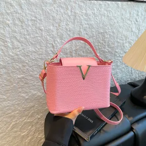 Sac à main rose en cuir tressé avec logo V doré présenté dans un cadre élégant