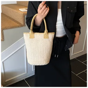 Close-up of beige herringbone straw bucket bag with contrasting yellow woven handles