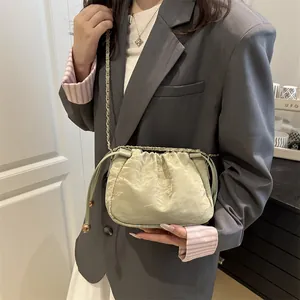 Light green drawstring bucket bag with crinkled texture and metal chain strap