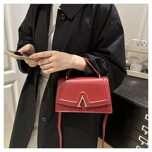 Detailansicht der roten Ledertasche mit goldener V-Metallschnalle und feiner Verarbeitung