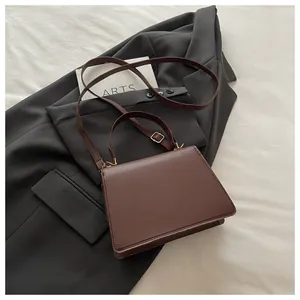 Detail einer braunen Lederhandtasche mit goldfarbenen Beschlägen und einem Tragegriff