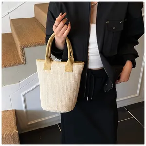 Detailed view of beige woven bucket bag with fabric handles styled on a casual outfit