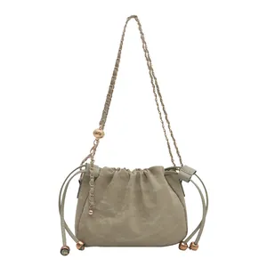 Pale green drawstring bucket bag with gold chain strap and adjustable metal ball