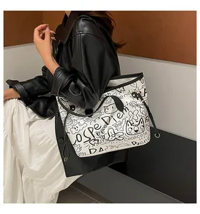 Dettaglio della borsa tote bianca con stampe graffiti nere e sottili manici in pelle
