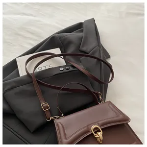 Nahaufnahme einer braunen Ledertasche mit goldenem Doppelring-Verschluss und Klappe