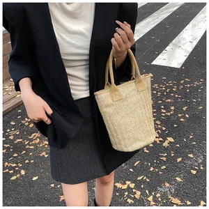 Detailed shot of a large straw bucket bag with brown handles in an outdoor setting
