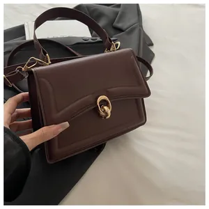 Nahaufnahme der dunkelbraunen Lederhandtasche mit goldenem Ringverschluss und Ziernähten