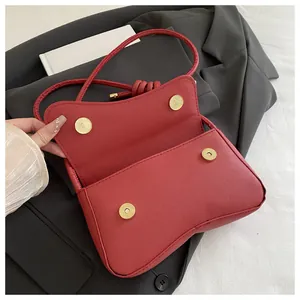 Detail van rode cross-grain leren tas met gouden magneetsluitingen en geknoopte schouderband