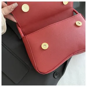 Detailopname van rode Saffiano leren baguette tas met dubbele gouden magneetsluiting